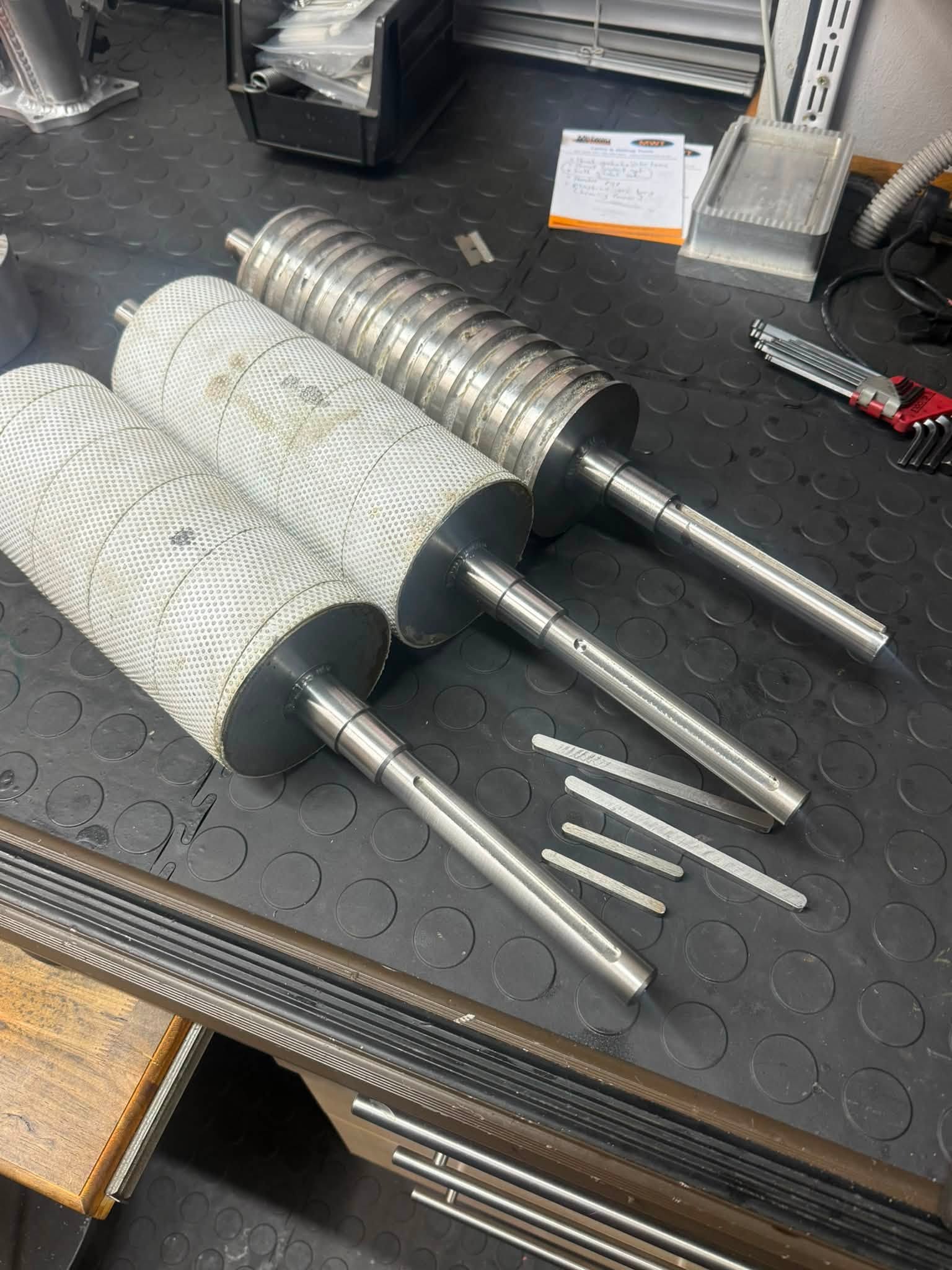 Industrial roller shafts with machined ends and keyways on the HondaWorx workbench.